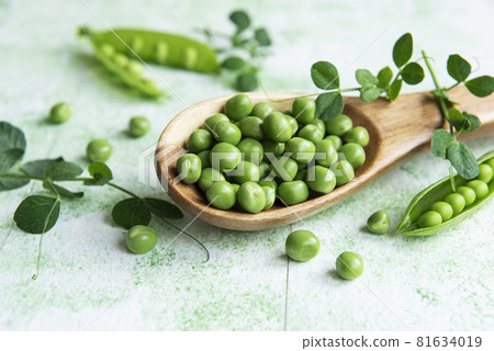 Fresh green peas pods and green peas with sprouts on green wooden background. Fresh green peas pods and green peas with sprouts on green wooden background. 81634019