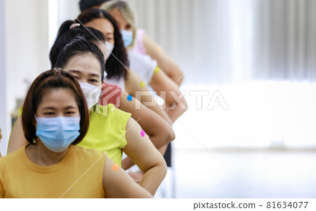 Group of diverse female stnad in row line show their colorful plaster on shoulder together after vaccinating in blurred background Group of diverse female stnad in row line show their colorful plaster on shoulder together after vaccinating in blurred background 81634077
