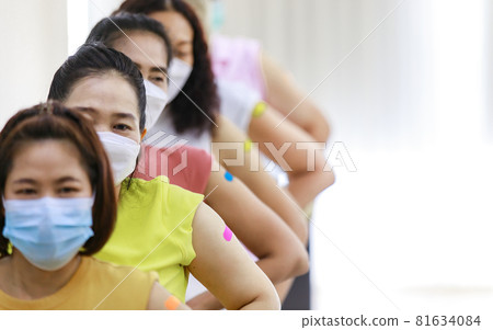 Group of diverse female stnad in row line show their colorful plaster on shoulder together after vaccinating in blurred background Group of diverse female stnad in row line show their colorful plaster on shoulder together after vaccinating in blurred background 81634084