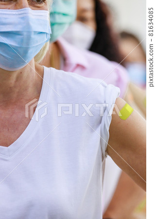 Group of diverse female populations stnad in multinational ethnics queue line show their colorful plaster on shoulder together after vaccinating in blurred background Group of diverse female populations stnad in multinational ethnics queue line show their colorful plaster on shoulder together after vaccinating in blurred background 81634085