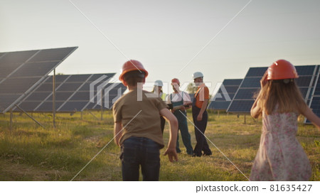 Two small children run to their parents who are at work. A solar power plant employee with children at work smiling at the camera. Three solar energy specialists at a solar power facility. Two small children run to their parents who are at work. A solar power plant employee with children at work smiling at the camera. Three solar energy specialists at a solar power facility. 81635427
