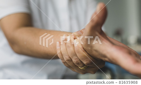 Woman in white clothes using hand to hold wrist with feeling pain, suffer, hurt and tingling. Concept of Guillain barre syndrome and numb hands disease 81635908