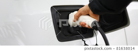 Driver inserts electric charger into vehicle closeup Driver inserts electric charger into vehicle closeup 81638014