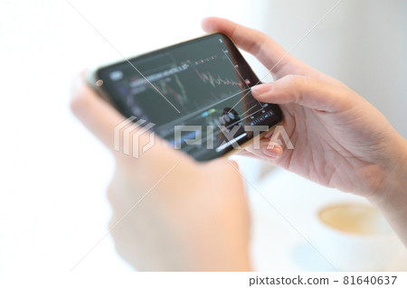 Female hand with smartphone trading stock online in coffee shop , Business concept Female hand with smartphone trading stock online in coffee shop , Business concept 81640637