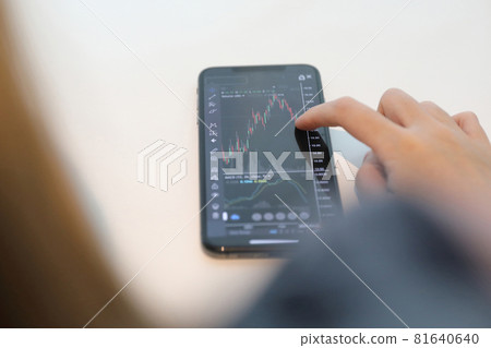 Female hand with smartphone trading stock online in coffee shop , Business concept Female hand with smartphone trading stock online in coffee shop , Business concept 81640640