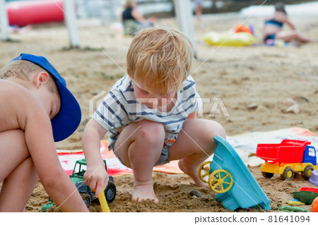 Two children play in the sand with plastic toys 81641094
