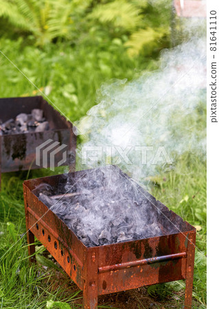 Firing up an old rusty metal barbecue grill, smoke and fire 81641110