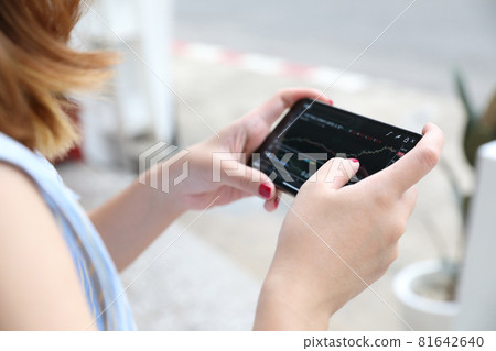 Female hand with smartphone trading stocks online in coffee shop Business concept Female hand with smartphone trading stocks online in coffee shop Business concept 81642640