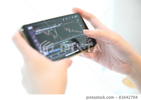 Female hand with smartphone trading stock online in coffee shop , Business concept 81642704