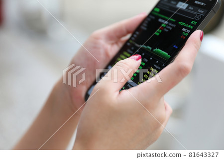 Female hand with smartphone trading stocks online in coffee shop Business concept Female hand with smartphone trading stocks online in coffee shop Business concept 81643327