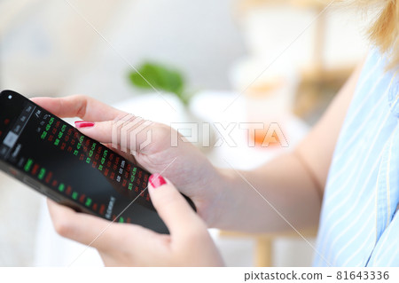 Female hand with smartphone trading stocks online in coffee shop Business concept Female hand with smartphone trading stocks online in coffee shop Business concept 81643336