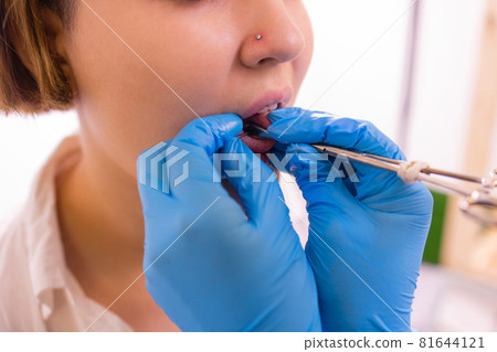 Close up portrait of young Caucasian woman sticking out pierced tongue. Close up portrait of young Caucasian woman sticking out pierced tongue. 81644121