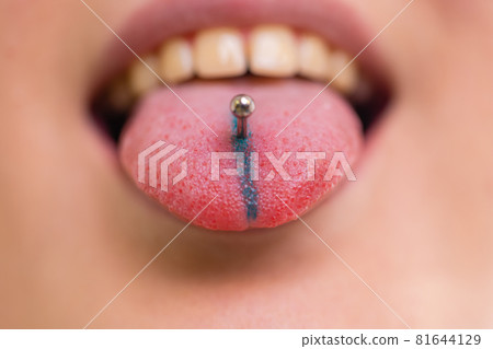 Close up portrait of young Caucasian woman sticking out pierced tongue. Close up portrait of young Caucasian woman sticking out pierced tongue. 81644129