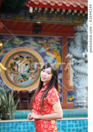 beauty woman wear red cheongsam looking and smile in chinese new year 81644144