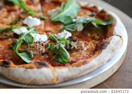 Italian Sausage and rocket salad pizza on wood background Italian Sausage and rocket salad pizza on wood background 81645172