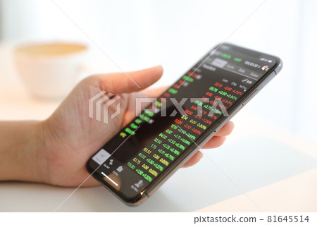 Female hand with smartphone trading stock online in coffee shop , Business concept Female hand with smartphone trading stock online in coffee shop , Business concept 81645514