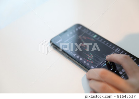 Female hand with smartphone trading stock online in coffee shop , Business concept Female hand with smartphone trading stock online in coffee shop , Business concept 81645537