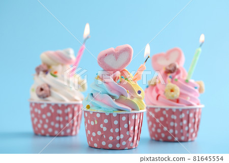 Colorful cupcakes with candle isolated in blue background Colorful cupcakes with candle isolated in blue background 81645554