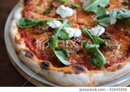 Italian Sausage and rocket salad pizza on wood background Italian Sausage and rocket salad pizza on wood background 81645806