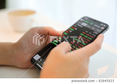 Female hand with smartphone trading stock online in coffee shop , Business concept 81645815