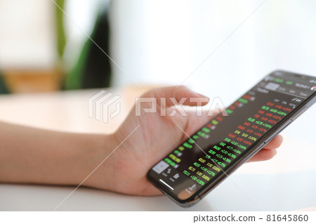 Female hand with smartphone trading stock online in coffee shop , Business concept 81645860