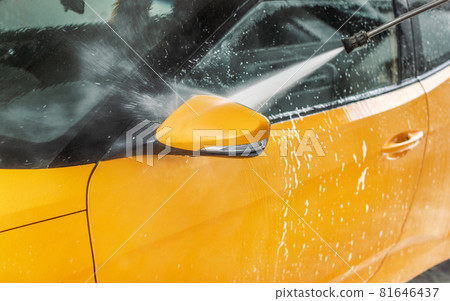 Side mirror of car washed in self serve carwash, jet water spraying from high pressure hose nozzle. Side mirror of car washed in self serve carwash, jet water spraying from high pressure hose nozzle. 81646437