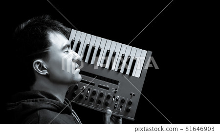 black and white portrait of asian handsome musician holding analog synthesizer keyboard, isolate on black. music background black and white portrait of asian handsome musician holding analog synthesizer keyboard, isolate on black. music background 81646903