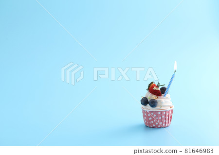 Colorful cupcake with candle isolated in blue background Colorful cupcake with candle isolated in blue background 81646983