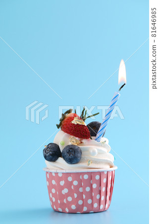 Colorful cupcake with candle isolated in blue background 81646985