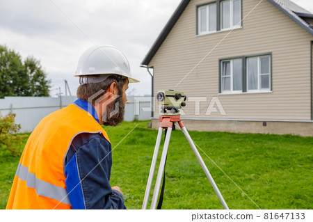 A male engineer works with the optical level on site. A male engineer works with the optical level on site. 81647133