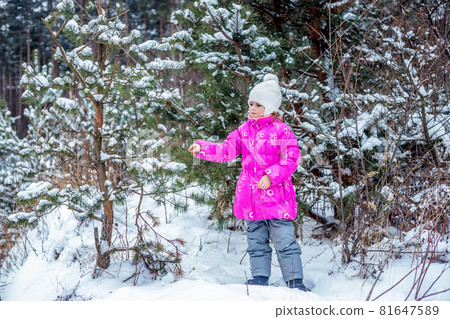 Caucasian girl of 5 years playing in the winter forest, spending time outdoors 81647589
