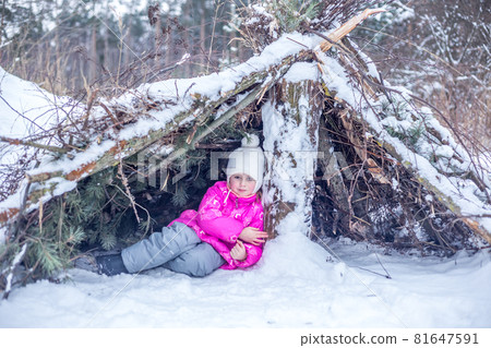 Caucasian girl hides in a hut from coniferous branches in the winter forest Caucasian girl hides in a hut from coniferous branches in the winter forest 81647591