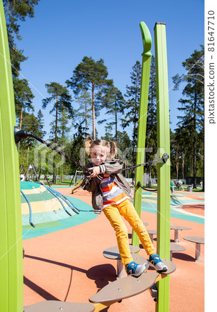 little girl climbs the suspension bridge at the playground outdoors little girl climbs the suspension bridge at the playground outdoors 81647710