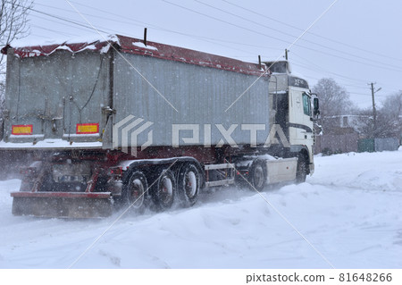 Winter. A large lorry, a wagon, is driving along a snow-covered road. Winter. A large lorry, a wagon, is driving along a snow-covered road. 81648266