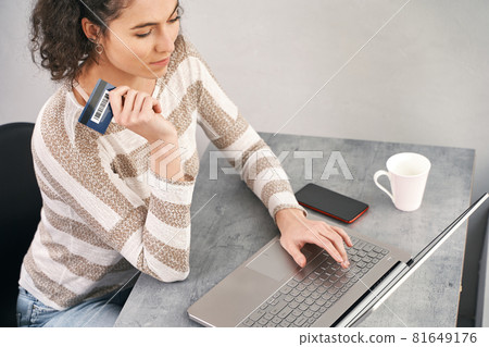Happy woman holding credit card and using laptop for buying online Happy woman holding credit card and using laptop for buying online 81649176