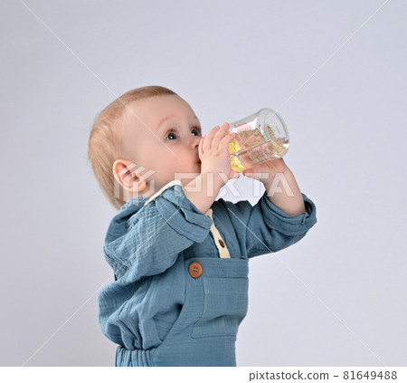 adorable child drinking from bottle. 81649488