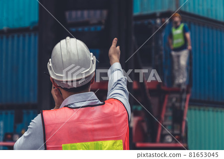 Industrial worker works with co-worker at overseas shipping container yard Industrial worker works with co-worker at overseas shipping container yard 81653045