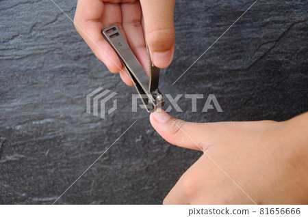 Hand holding and using nail clippers Hand holding and using nail clippers 81656666