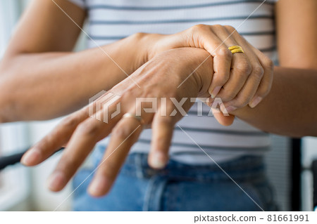 Woman in using hand to hold wrist and stretching fingers. with feeling pain, suffer, hurt and tingling. Concept of Guillain barre syndrome and numb hands disease 81661991
