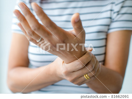 Woman in using hand to hold wrist and stretching fingers. with feeling pain, suffer, hurt and tingling. Concept of Guillain barre syndrome and numb hands disease 81662091