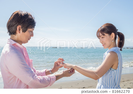 A couple handing a ring at the beach in a sunny summer 81662270