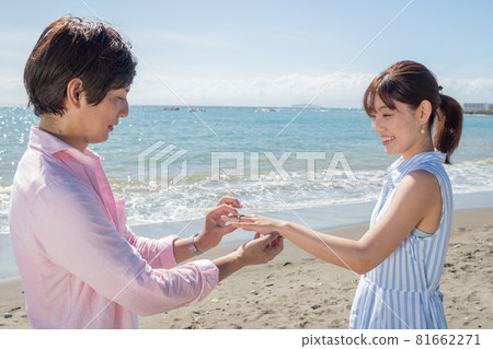 A couple handing a ring at the beach in a sunny summer 81662271
