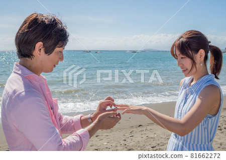 A couple handing a ring at the beach in a sunny summer A couple handing a ring at the beach in a sunny summer 81662272