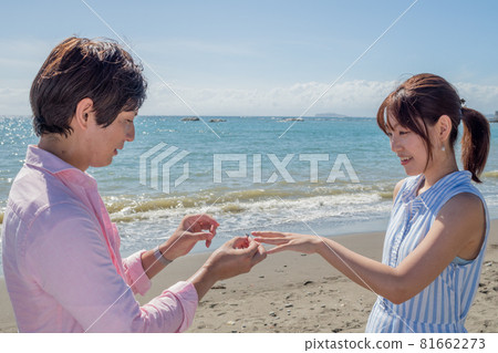 陽光明媚的夏天,一對夫婦在海灘上遞戒指 陽光明媚的夏天,一對夫婦在海灘上遞戒指 81662273