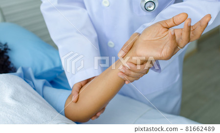 Doctor hold hand of patient on bed in hospital and checkup nervous system for cure and treatment. Concept of Guillain barre syndrome and numb hands disease or vaccine side effect Doctor hold hand of patient on bed in hospital and checkup nervous system for cure and treatment. Concept of Guillain barre syndrome and numb hands disease or vaccine side effect 81662489