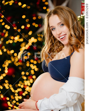 an attractive pregnant woman with a bare tummy near the christmas tree 81663269