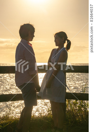 Couple facing each other at the beach at dusk in summer Couple facing each other at the beach at dusk in summer 81664037