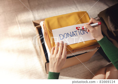 Clothes Donation Concept. Box of Cloth with Donate label. Woman Preparing Used Old Garment at Home. Top View 81669114