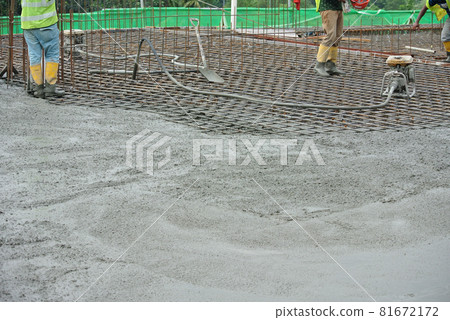 JASIN, MALAYSIA -NOVEMBER 13, 2015: Construction worker leveling wet concrete has been poured. They also use a vibrator machine in this work. JASIN, MALAYSIA -NOVEMBER 13, 2015: Construction worker leveling wet concrete has been poured. They also use a vibrator machine in this work. 81672172