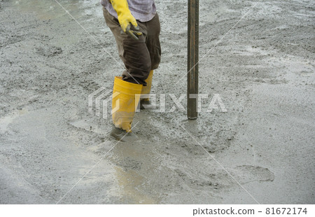 JASIN, MALAYSIA -NOVEMBER 13, 2015: Construction worker leveling wet concrete has been poured. They also use a vibrator machine in this work. JASIN, MALAYSIA -NOVEMBER 13, 2015: Construction worker leveling wet concrete has been poured. They also use a vibrator machine in this work. 81672174